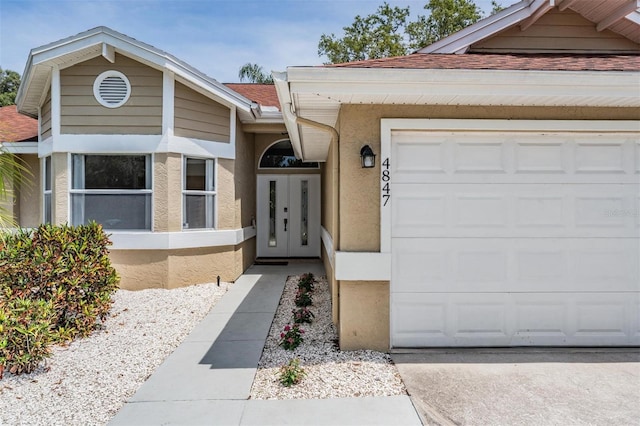 view of front of property featuring stucco siding, driveway, a shingled roof, and an attached garage