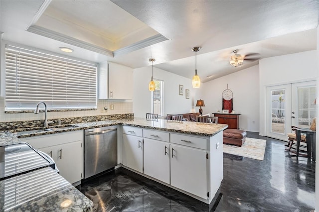 kitchen featuring tasteful backsplash, stainless steel dishwasher, a sink, a tray ceiling, and a peninsula