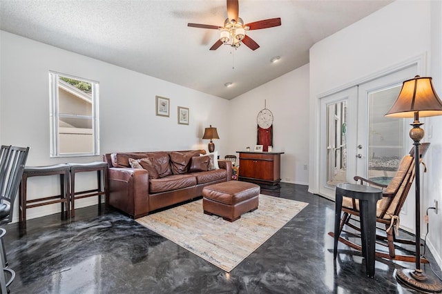 living area featuring finished concrete flooring, a ceiling fan, lofted ceiling, and baseboards