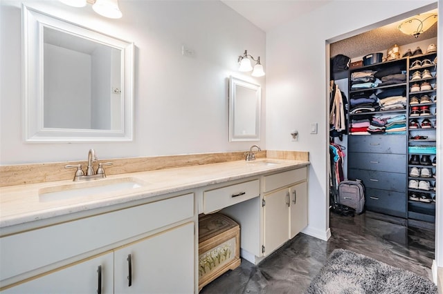 full bathroom featuring a walk in closet, double vanity, a sink, and marble finish floor