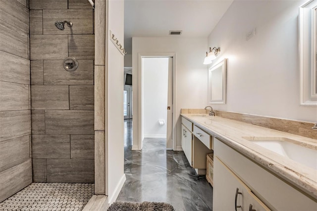 bathroom featuring visible vents, tiled shower, double vanity, and a sink