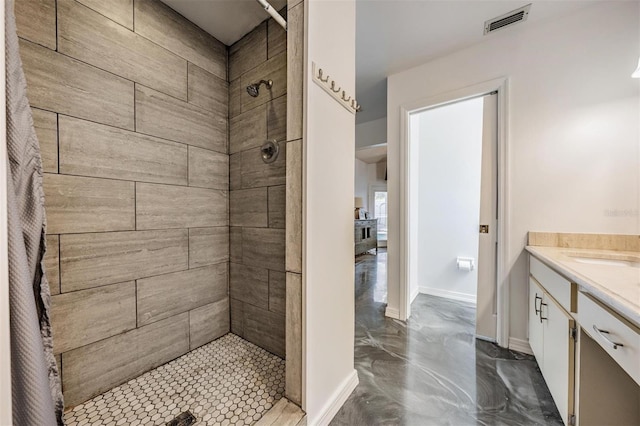 full bath with visible vents, tiled shower, vanity, and baseboards