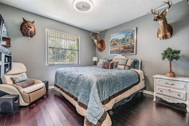 bedroom with wood-type flooring, a textured ceiling, and baseboards