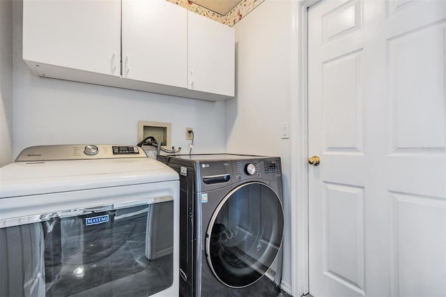 clothes washing area with washer and dryer and cabinet space