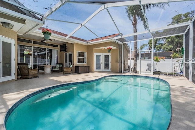 view of swimming pool featuring a ceiling fan, a patio area, french doors, and glass enclosure