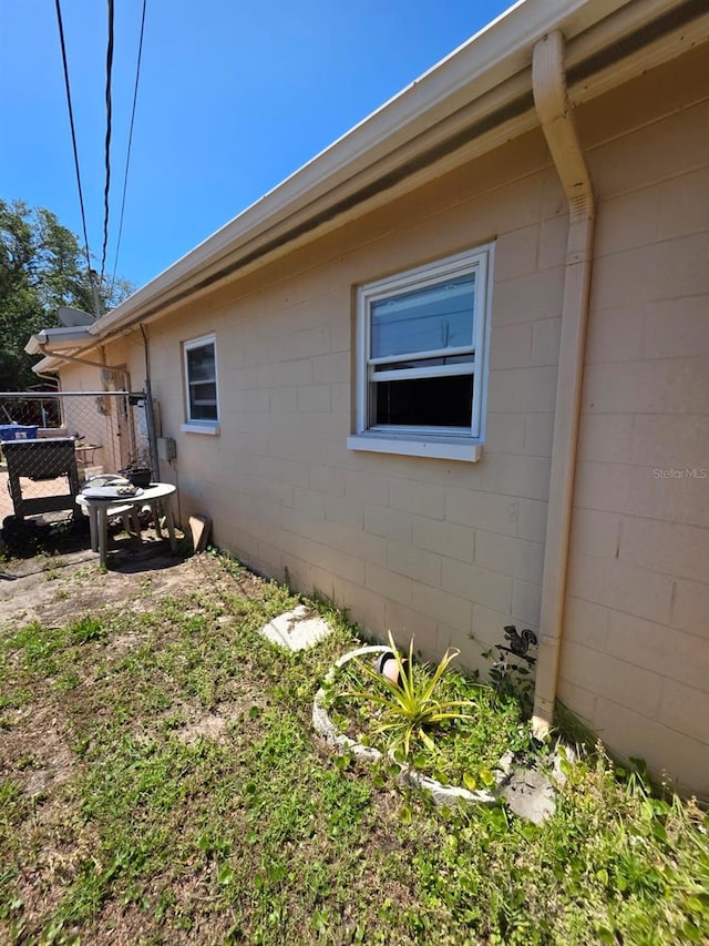view of home's exterior with fence and concrete block siding