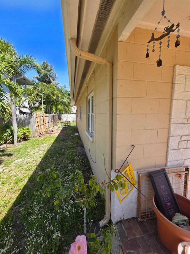 view of home's exterior featuring fence, concrete block siding, and a yard
