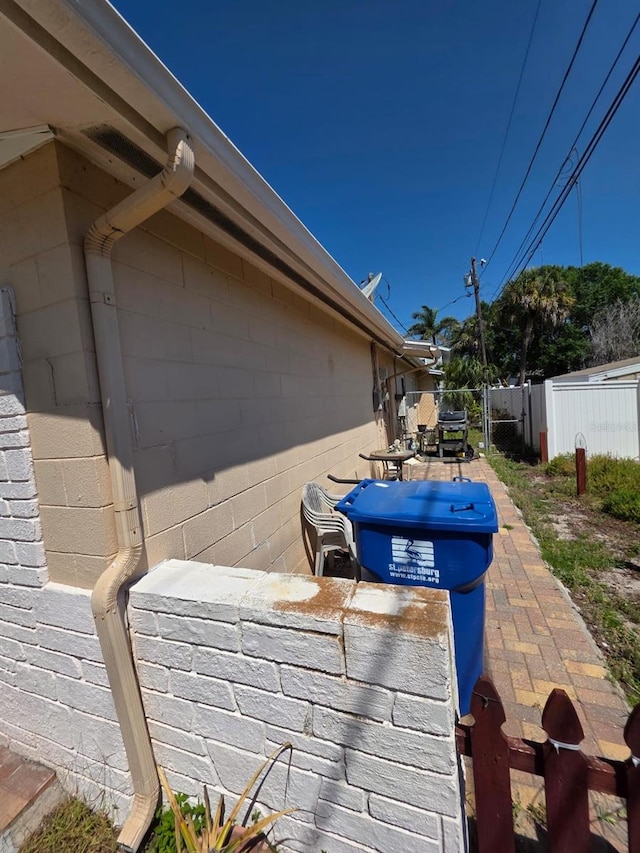 view of home's exterior with fence, concrete block siding, and a patio