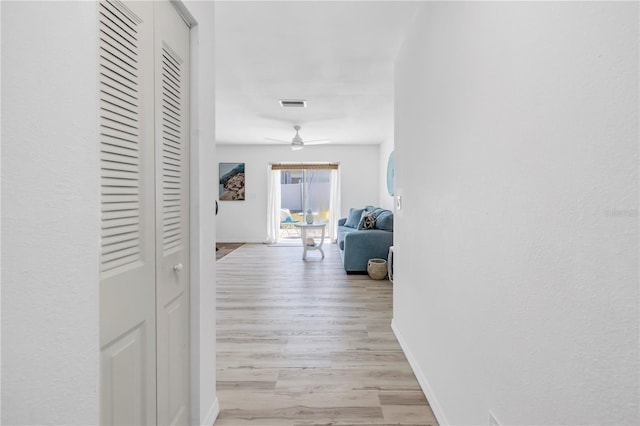 hallway featuring visible vents, wood finished floors, and baseboards