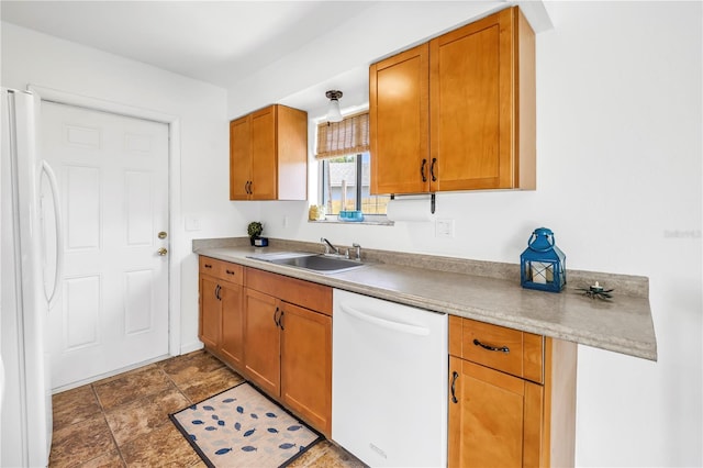 kitchen featuring light countertops, a sink, brown cabinetry, and white appliances