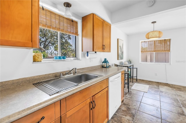kitchen with pendant lighting, a sink, light countertops, white dishwasher, and brown cabinetry