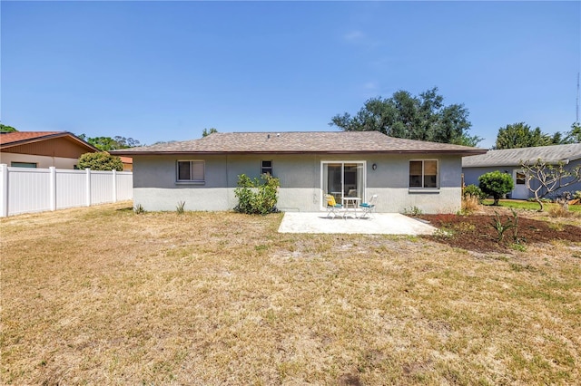 rear view of house featuring a patio, fence, stucco siding, and a yard