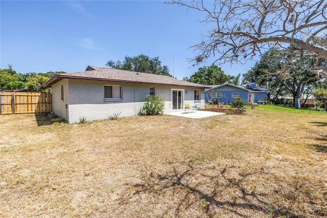 back of house with a patio, a lawn, stucco siding, and fence