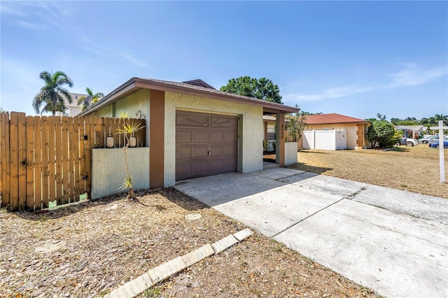 view of front of house featuring fence, stucco siding, driveway, and an attached garage
