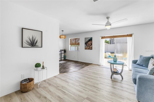 living room featuring wood finished floors, a ceiling fan, and baseboards