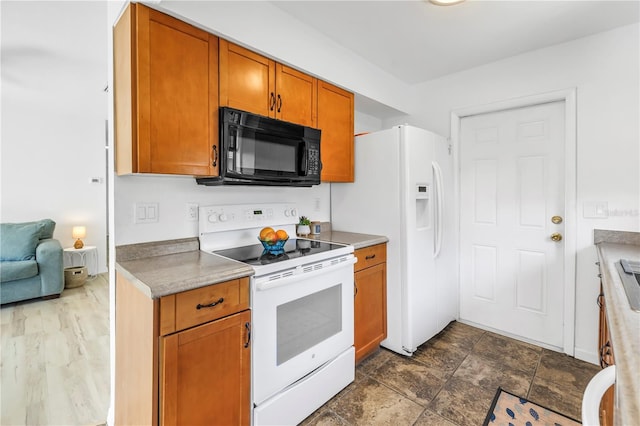 kitchen featuring white appliances, light countertops, and brown cabinetry