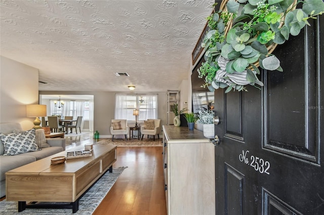 entrance foyer with visible vents, baseboards, a textured ceiling, and wood finished floors