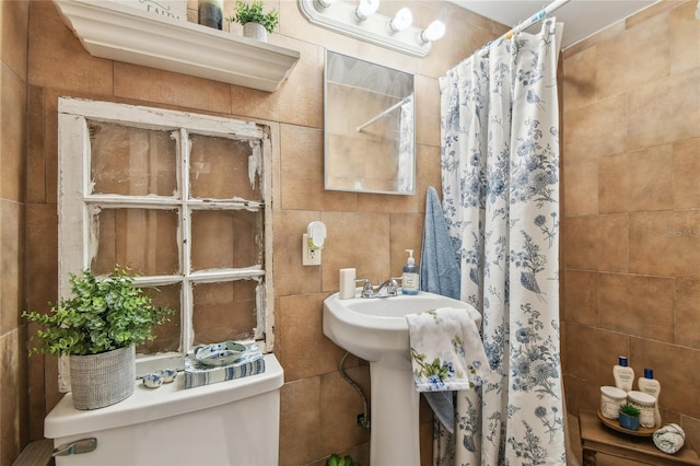 bathroom featuring tile walls, a tile shower, and toilet