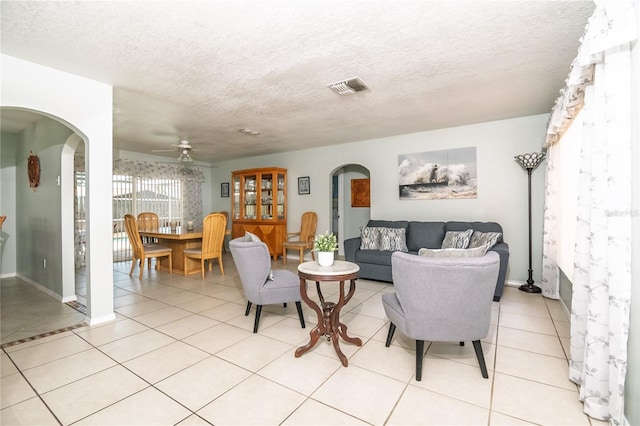 7812 Turnbridge Dr, Port Richey, FL 34668 - living room featuring arched walkways, ceiling fan, a textured ceiling, light tile patterned flooring, and baseboards