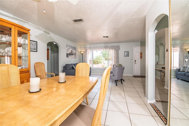7812 Turnbridge Dr, Port Richey, FL 34668 - dining area with arched walkways, light tile patterned floors, a textured ceiling, and baseboards