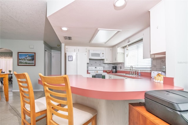 7812 Turnbridge Dr, Port Richey, FL 34668 - kitchen featuring white appliances, tasteful backsplash, white cabinetry, a sink, and a peninsula