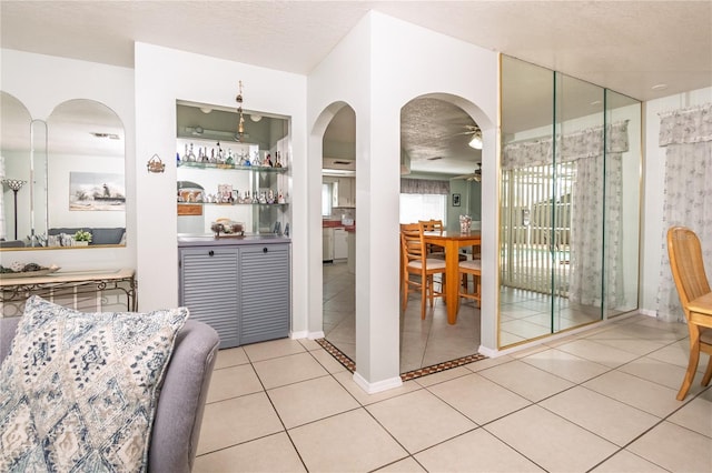7812 Turnbridge Dr, Port Richey, FL 34668 - dining area featuring a ceiling fan, arched walkways, light tile patterned flooring, and a textured ceiling