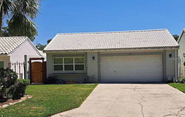 view of front of property with a front yard, a garage, driveway, a tiled roof, and stucco siding