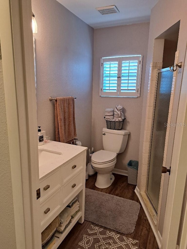 full bath featuring wood finished floors, toilet, vanity, visible vents, and a stall shower