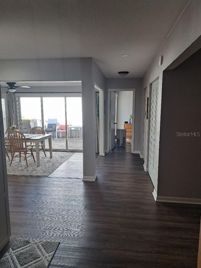 hallway featuring dark wood-type flooring and baseboards