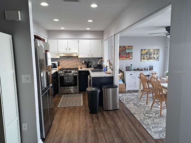 kitchen featuring under cabinet range hood, light countertops, appliances with stainless steel finishes, a sink, and dark wood-style floors