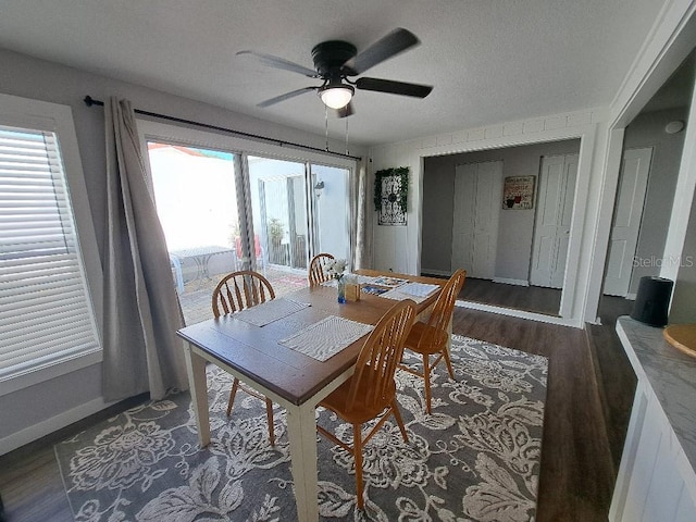 dining area with baseboards, a ceiling fan, and dark wood-type flooring