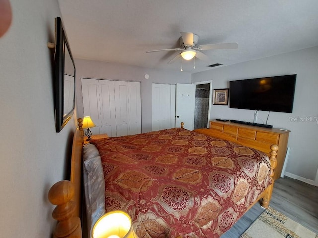 bedroom with wood finished floors, two closets, ceiling fan, baseboards, and visible vents