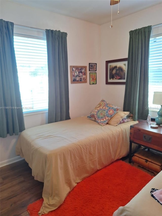 bedroom featuring baseboards, wood finished floors, and multiple windows