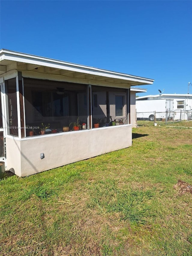 rear view of property with a yard, a sunroom, and fence