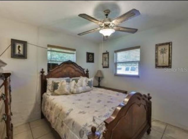 bedroom with a ceiling fan, multiple windows, and light tile patterned floors