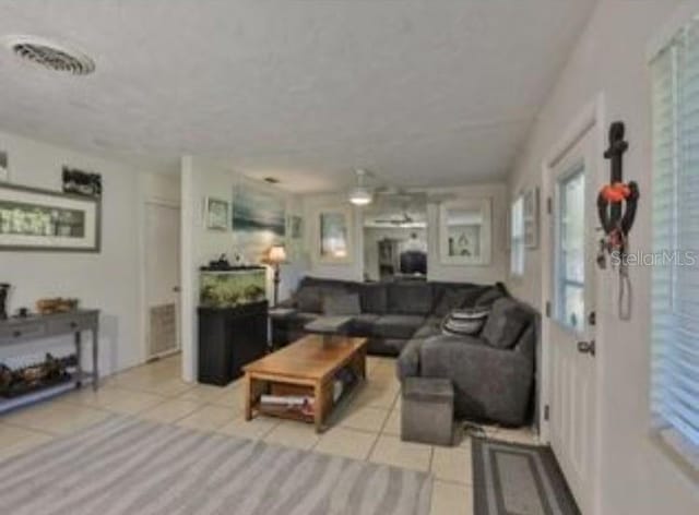living area featuring plenty of natural light, visible vents, a textured ceiling, and light tile patterned floors