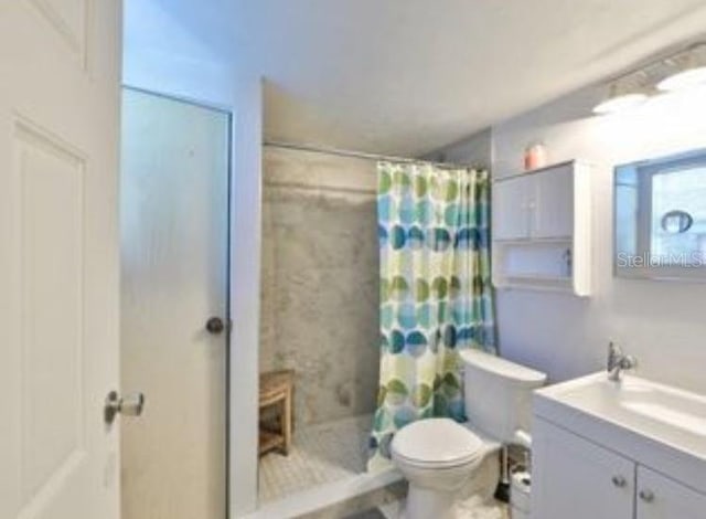 bathroom featuring vanity, toilet, and tiled shower