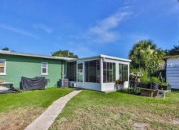 back of property with cooling unit, a yard, and a sunroom