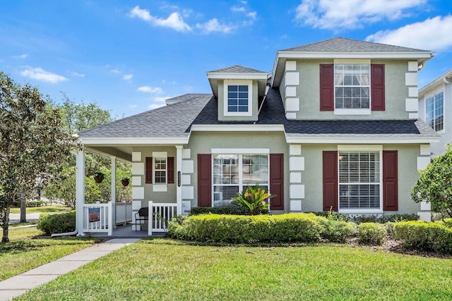 view of front of property featuring a porch, a shingled roof, a front yard, and stucco siding