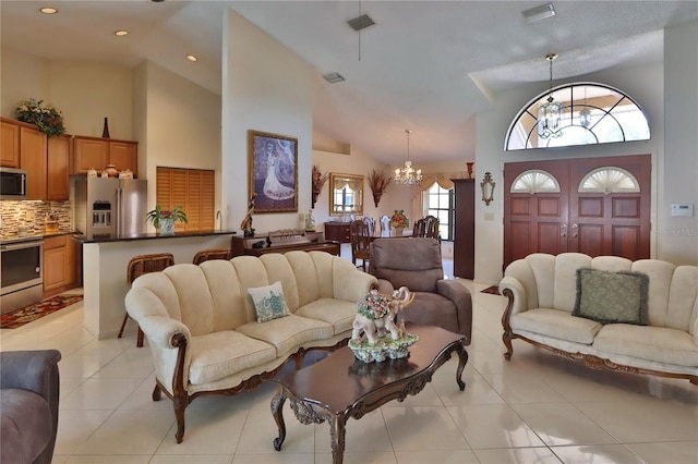living room with an inviting chandelier, high vaulted ceiling, light tile patterned flooring, and visible vents