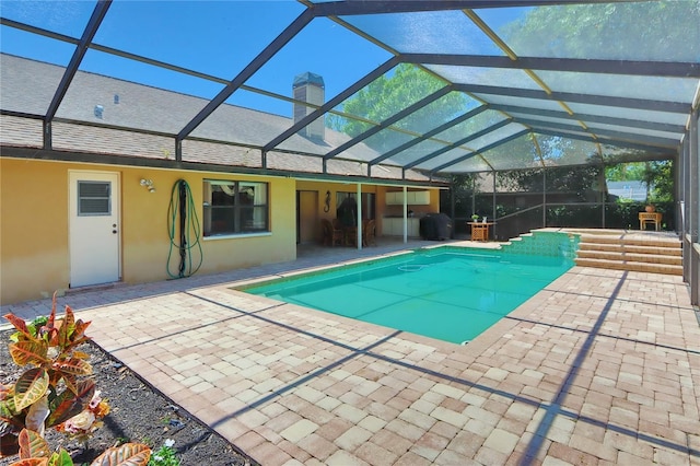 pool featuring glass enclosure and a patio