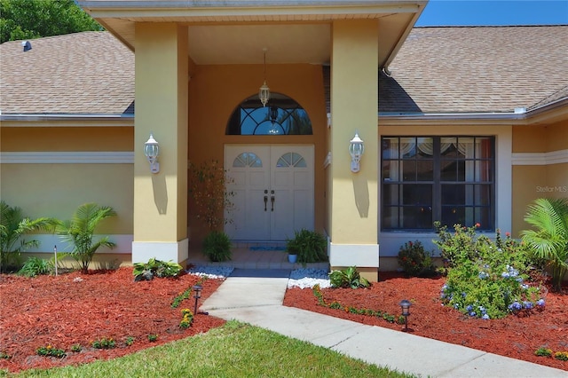property entrance with a shingled roof and stucco siding