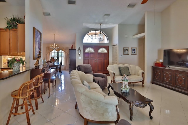 living area with visible vents, light tile patterned floors, and a towering ceiling