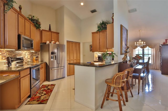 kitchen with decorative backsplash, visible vents, high vaulted ceiling, a chandelier, and stainless steel appliances