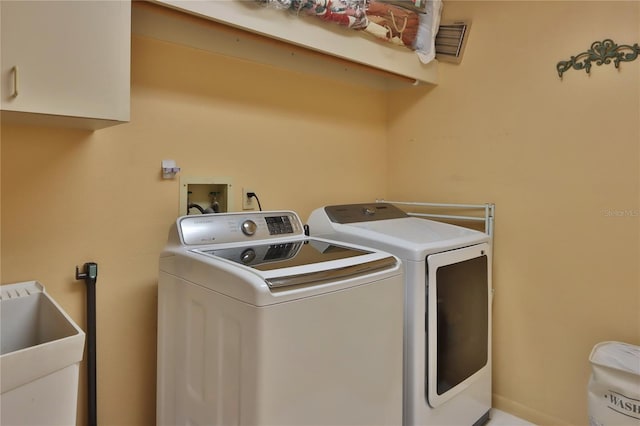 clothes washing area with visible vents, a sink, cabinet space, and washing machine and dryer