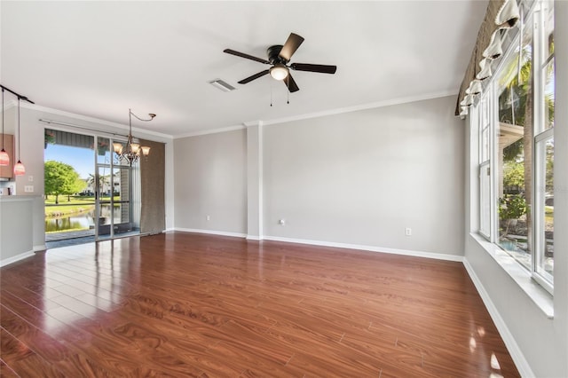 spare room featuring crown molding, ceiling fan with notable chandelier, baseboards, visible vents, and dark wood-type flooring