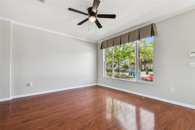 empty room featuring ornamental molding, ceiling fan, wood finished floors, and baseboards