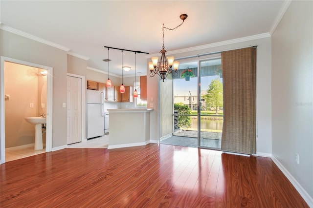 interior space with ornamental molding, baseboards, light wood finished floors, and a notable chandelier