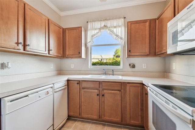 kitchen featuring white appliances, crown molding, brown cabinetry, and a sink