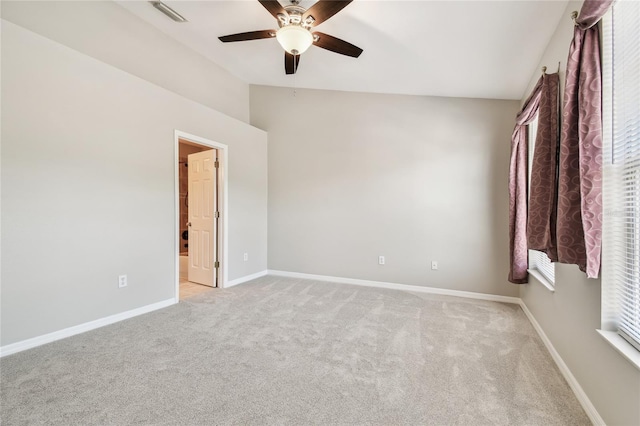 empty room featuring lofted ceiling, light colored carpet, a ceiling fan, and baseboards